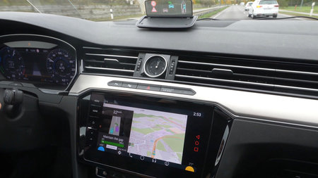 Die Mittelkonsole eines PKW mit einem Display, das Navgationsdaten zeigt.