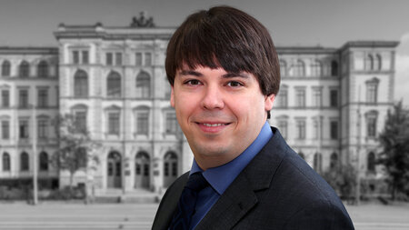 A young man in a suits smiles.